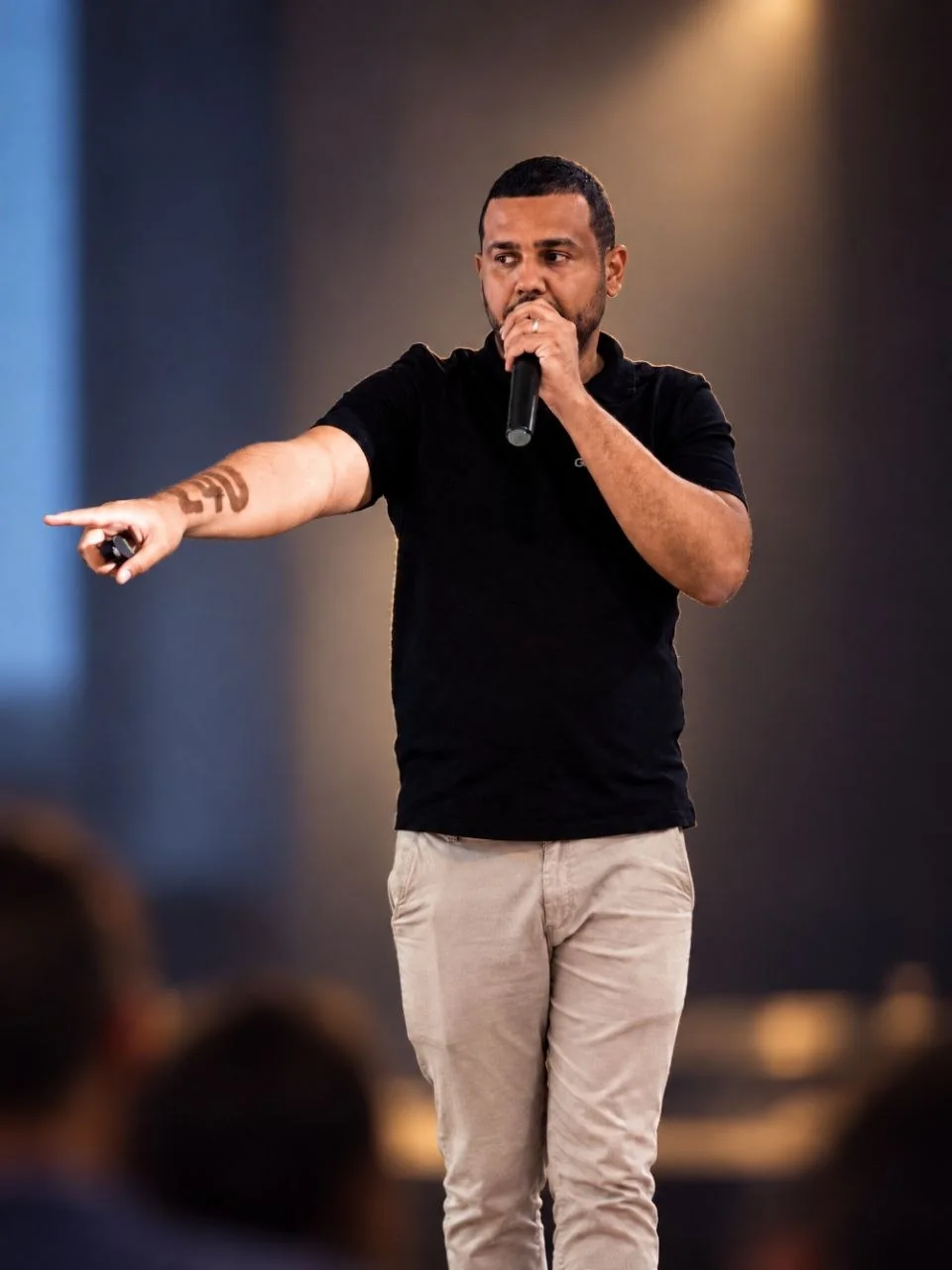 Brahimã Costa no palco, de microfone na mão, conduzindo um workshop presencial